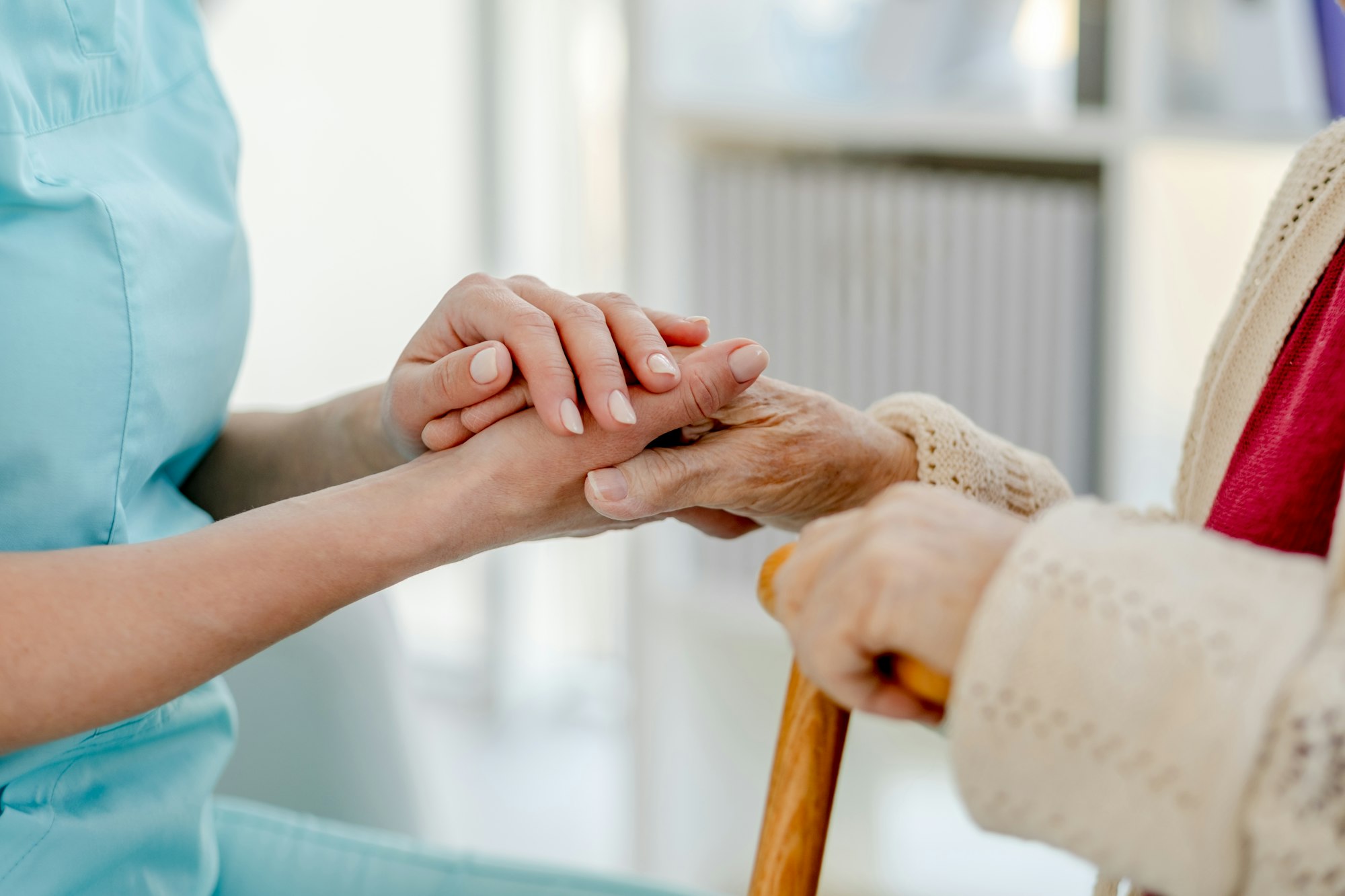 Close-Up Of Nurse'S Hand Holding Elderly Woman'S Hand With Cane