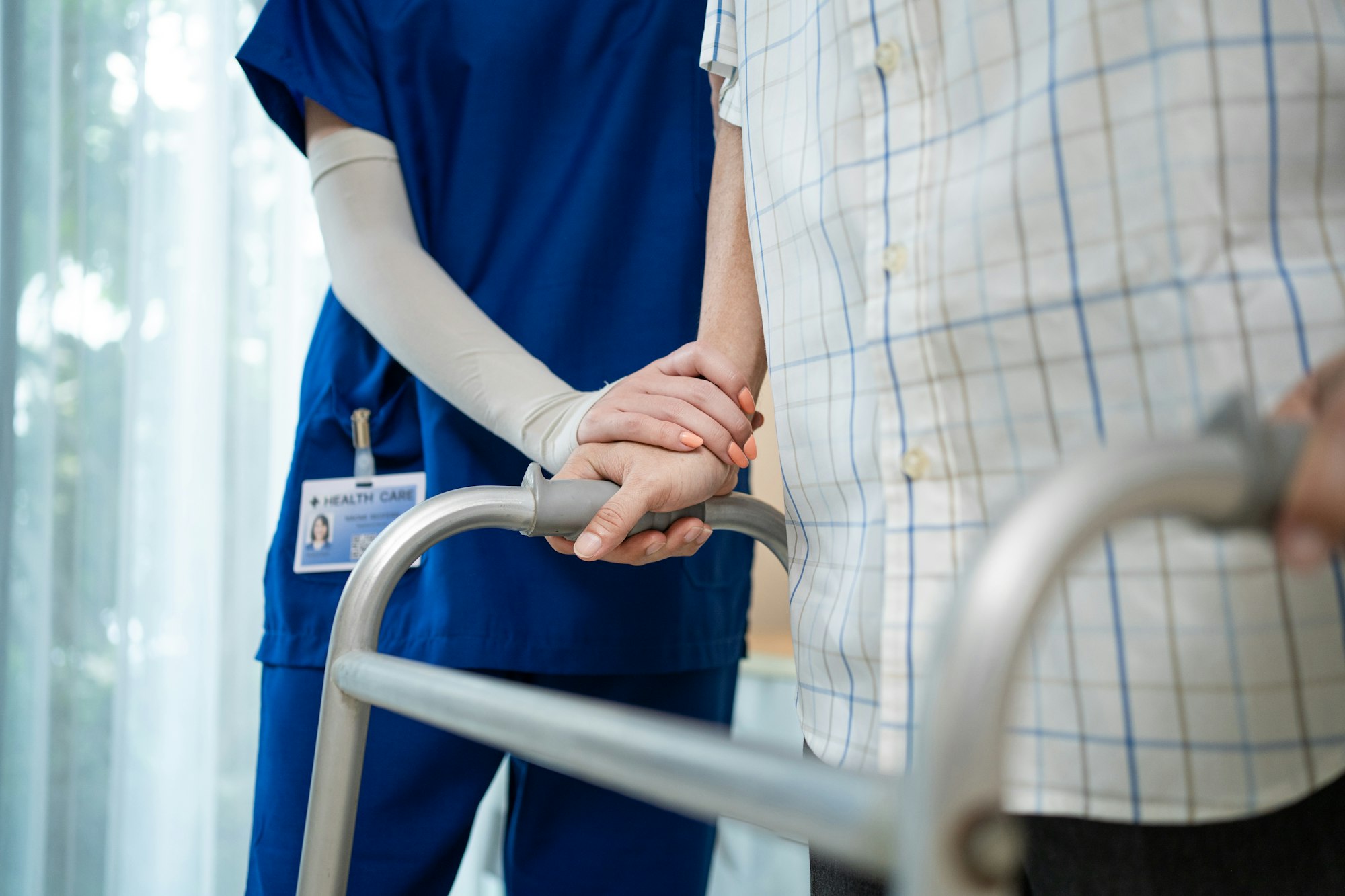 Close up of nurse help disable man walk with walker at nursing home.